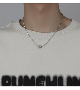 Close-up of minimalist silver snake chain necklace with checkerboard cylinder pendant
