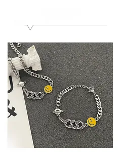 Dettaglio del bracciale a catena con smile giallo, ciondolo saturno e zirconi viola