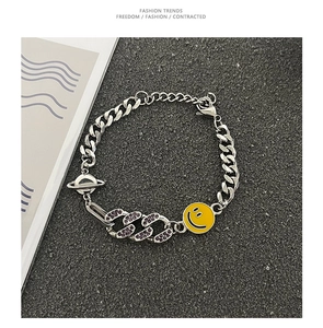 Dettaglio catena cubana punk argento con faccina gialla e strass viola scintillanti