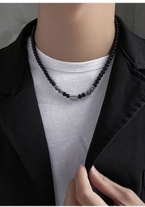 Primer plano de collar de obsidiana para hombre con detalle metálico sobre el modelo