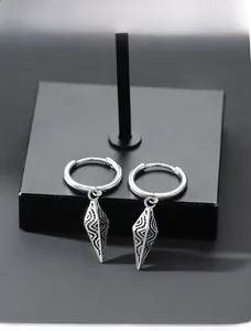 Close-up of vintage silver hoop earrings with textured cone pendants and geometric patterns