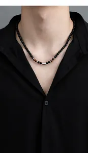 Primer plano de collar para hombre de cuentas de obsidiana y ojo de tigre sobre negro
