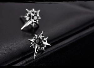 Macro detail of silver star stud earrings with black center stone on leather texture