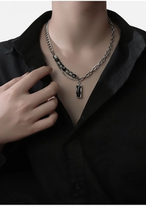 Détail d'un collier multicouche avec chaîne cubaine et pendentif rectangle sur homme