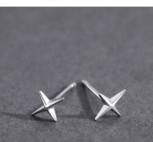 Gros plan de boucles d'oreilles étoiles à quatre branches en argent poli au fini miroir