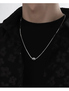 Chaîne serpent argentée avec pendentif mantra rotatif sur mannequin homme en noir