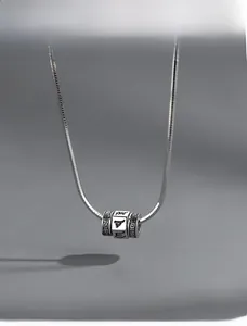 Vue détaillée du pendentif cylindre rotatif avec mantra gravé sur chaîne serpent argent