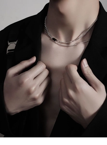Détail d'un collier double épaisseur argenté avec pendentif rectangulaire noir pour homme