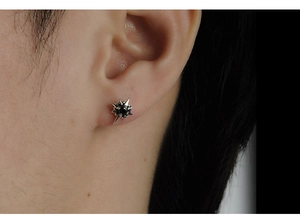 Macro shot of silver starburst stud earrings featuring a centered black zircon stone