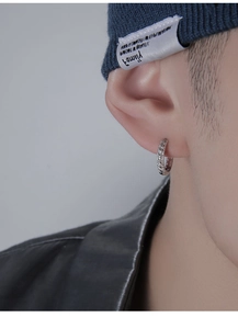 Gros plan d'une boucle d'oreille créole argentée torsadée pour homme portée par un mannequin