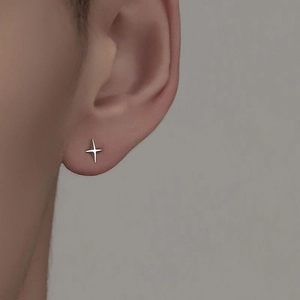 Gros plan d'une boucle d'oreille étoile argentée polie portée sur le lobe d'oreille