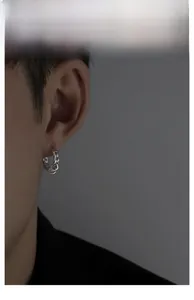 Macro shot of a silver Cuban chain style earring worn on a male model for street style