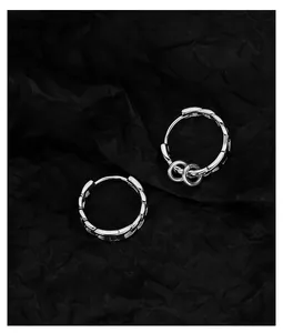 Close-up of polished silver chain earrings with dangling ring details on black background