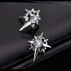 Macro shot of silver North Star stud earrings with sparkling cubic zirconia on black leather