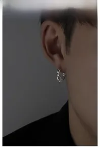 Close-up of a silver chain link earring with hanging rings on a male ear