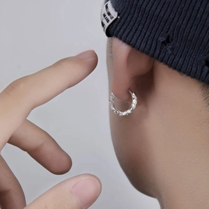 Irregular textured silver hoop earring with rock finish on male model with beanie