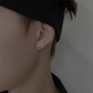 Unisex silver North Star stud earring with black zircon stone on male model ear