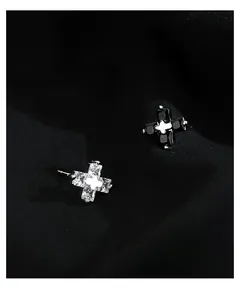 Close-up of cross stud earrings with sparkling crystals on black silk fabric