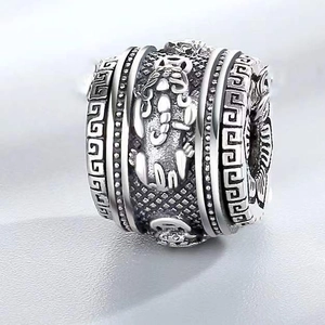Macro shot of silver cylinder bead featuring intricate dragon relief and Greek meander patterns