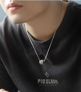Close-up of a silver cylinder pendant with vintage engraving on a chain necklace