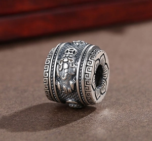 Macro shot of vintage silver charm with embossed PiXiu and lotus flower patterns
