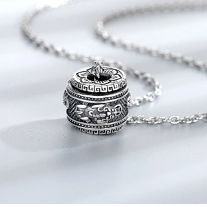 Macro detail of vintage S925 silver cylinder pendant with intricate dragon carvings