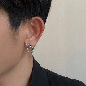 Close-up of star-shaped chain earring with black stone on male model ear