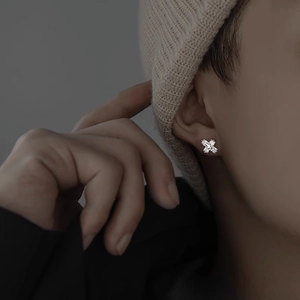 Cross-shaped sterling silver stud earring with sparkling zircons worn by a male model