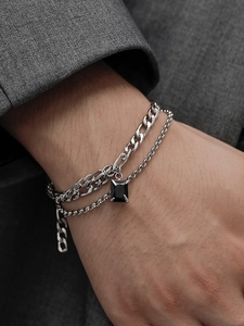 Detail of silver double-layered chain bracelet with a black rectangular gemstone pendant