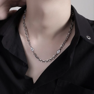 Détail d'un collier argenté avec pendentif en losange et motif étoile sur une chemise noire