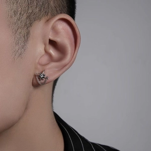 Macro view of silver star stud earring with white zircon and delicate metal chain on ear