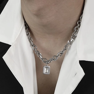 Detail of silver chain necklace with rectangular zircon pendant worn over a suit
