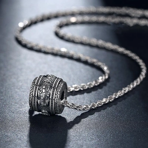 Detailed macro view of an engraved cylindrical dragon pendant on a rope chain necklace
