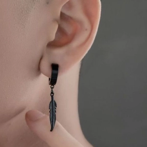 Détail d'une boucle d'oreille plume noire en titane montrant texture et port