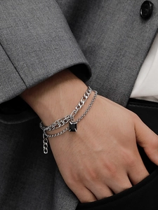 Detail of men's silver titanium double-layer bracelet with black square pendant on suit