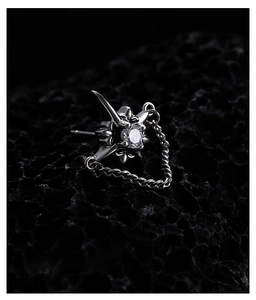 Macro shot of gothic black star stud earring with hanging chain and white zircon stone