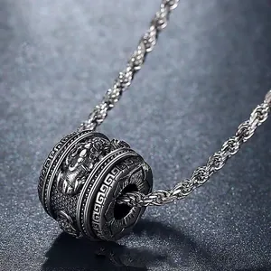 Close-up of vintage silver cylinder pendant with mythical beast and fret patterns
