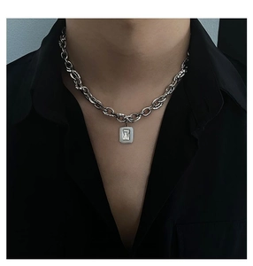 Detail of silver link chain necklace with rectangular zircon pendant on male model