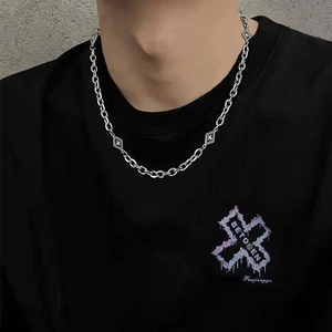 Collier avion losange argenté avec maillons à motif croisé pour homme sur t-shirt noir