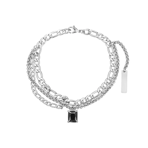 Detail of silver layered Figaro chain featuring black stone pendant and metal tag