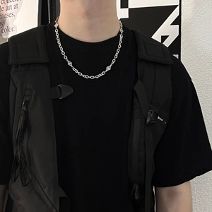 Détail du collier à chaîne à maillons argentés avec pendentifs géométriques en losange