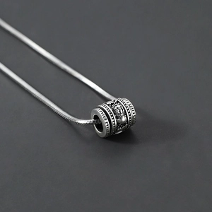 Macro shot of silver PiXiu cylinder pendant with detailed Chinese relief carvings