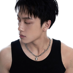 Detail view of hip-hop silver square zircon pendant necklace worn by male model on black vest