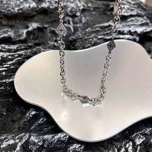 Détail macro de la chaîne argentée avec pendentifs en losange sur support miroir