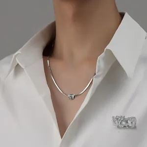 Macro detail of silver cylinder bead necklace with engraved patterns on snake chain