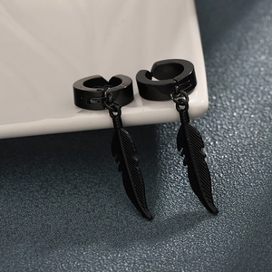 Boucles d'oreilles clips plume noire en acier titane sur un plateau en céramique