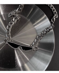 Macro shot of silver metal chain with black enamel sunglasses pendant and inlaid crystals