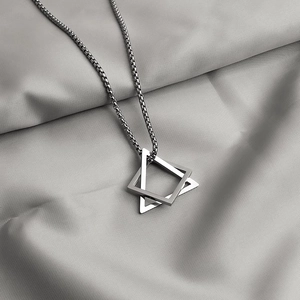 Detailed view of silver interlocking triangle pendant on a textured silk fabric background