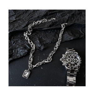 Close-up of hip hop silver link chain featuring a rectangular zircon pendant on black texture