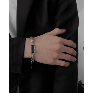 Gros plan d'un bracelet gourmette argenté pour homme avec pierre noire rectangulaire